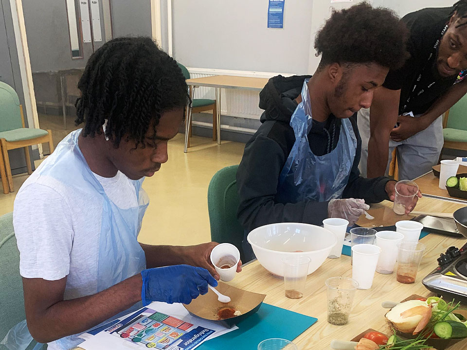 Young people learning how to cook jerk chicken bagels