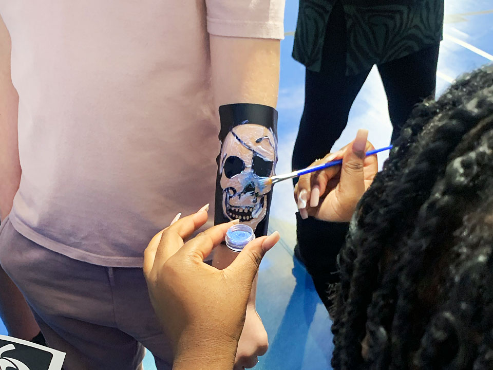 Young person getting a pirate skull painting on their arm.
