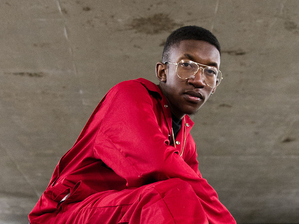 Young person crouching in a red boiler suit