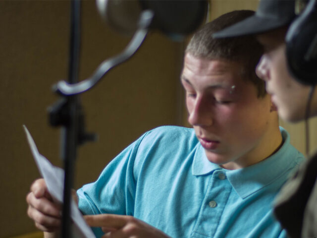 Two boys discussing lyrics in a recording studio session with the Music Ain't Diverse Enough project