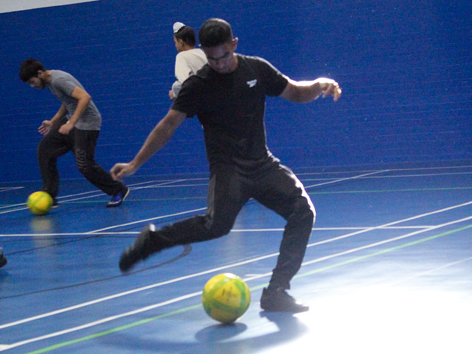 Teenager about to score a goal in an indoor football tournament
