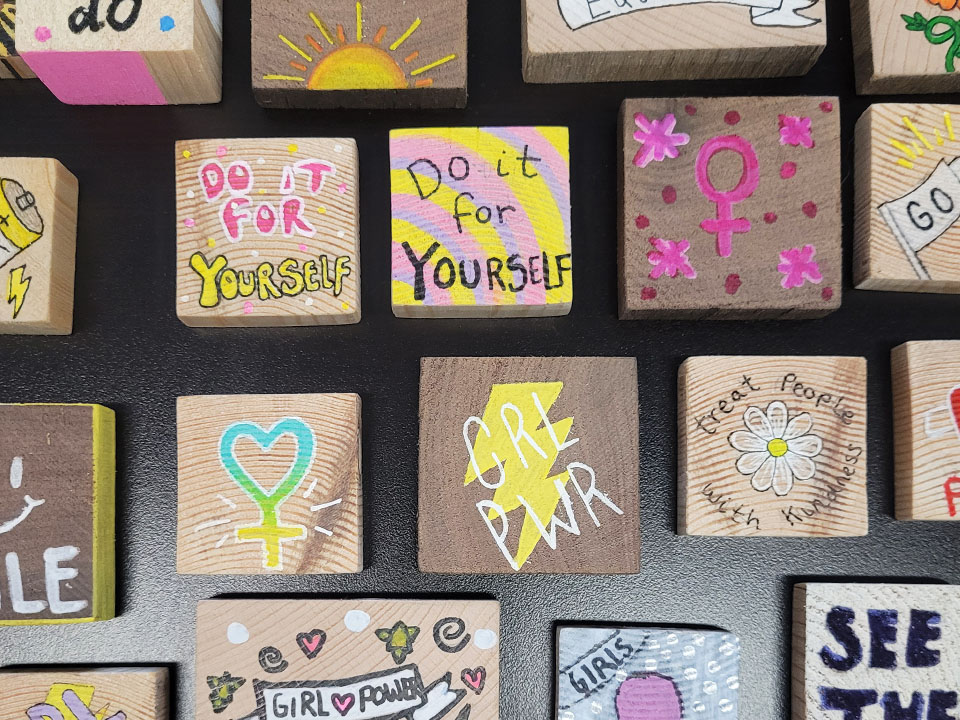 Collection of positive phrases painted on wooden blocks by Girls CAN participants
