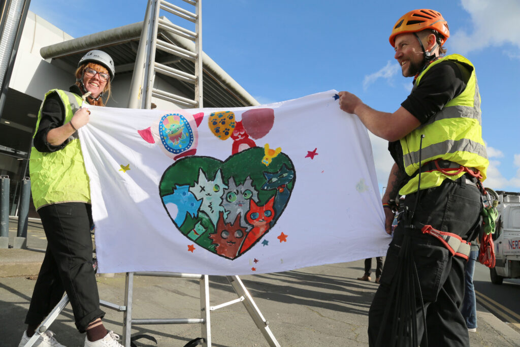 Artists-Leah-Anderson-and-Luke-Perry-preparing-to-climb-up-lampposts-to-display-flags-around-Stourbridge-Ring-Road